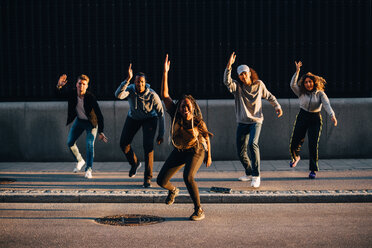 Multiethnische Freunde tanzen in voller Länge auf dem Bürgersteig in der Stadt - MASF11366
