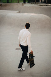 High angle view of man with skateboard walking at park - MASF11381