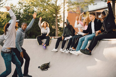 Friends dancing with hands raised in skateboard park - MASF11388