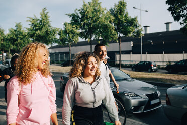 Fröhliche Freunde gehen auf der Straße neben Autos in der Stadt - MASF11410