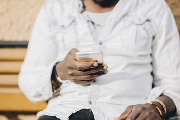 Midsection of man using smart phone on sunny day at yard - MASF11454