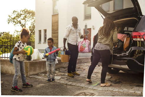 Familie in voller Länge mit Elektroauto in der Einfahrt zum Haus - MASF11459