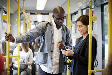 Multiethnische Pendler teilen ihr Smartphone, während sie in der Straßenbahn stehen - MASF11484