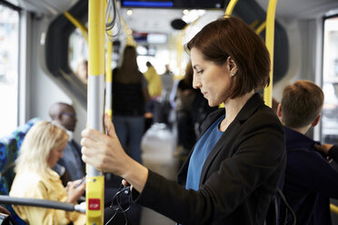 Side view of female commuter standing in bus - MASF11487