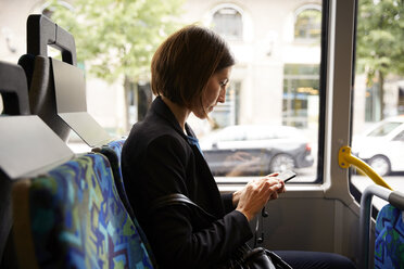 Side view of businesswoman using smart phone while sitting in bus - MASF11488