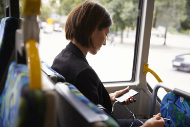 Mid adult businesswoman using smart phone while sitting in bus - MASF11490