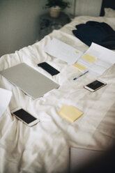 Hochformatige Ansicht von Technik und Papieren auf dem Bett einer Ferienvilla - MASF11518