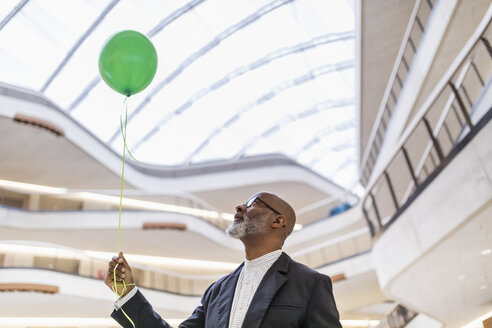 Älterer Geschäftsmann mit grünem Ballon - FMKF05364