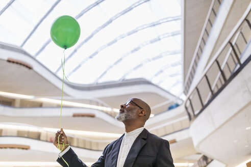 Mature businessman with green balloon - FMKF05364