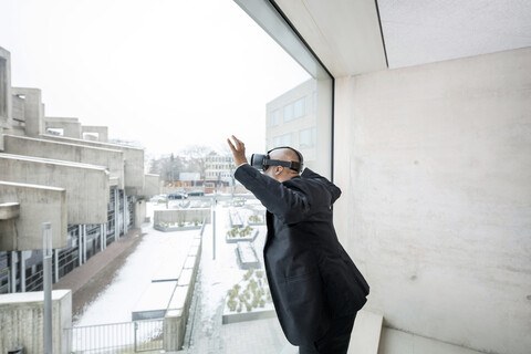 Mature businessman with Virtual Reality Glasses looking out of window stock photo