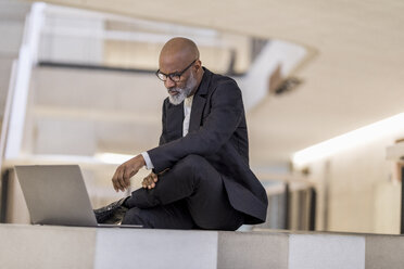 Bald mature businessman looking at laptop thinking - FMKF05398