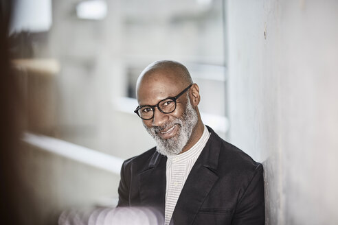 Portrait of smiling mature businessman with grey beard wearing glasses - FMKF05406