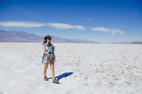 USA, Kalifornien, Death Valley National Park, Badwater Basin, glückliche Mutter, die mit ihrem kleinen Mädchen im Salzbecken spazieren geht, lizenzfreies Stockfoto