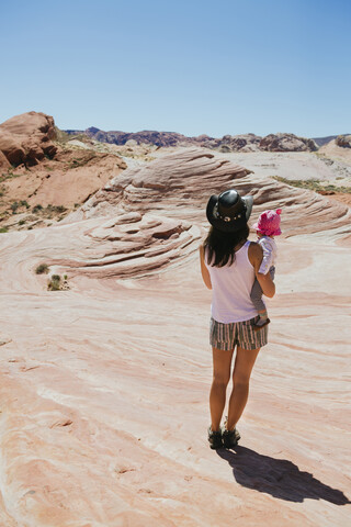 USA, Nevada, Valley of Fire State Park, Rückenansicht einer Mutter und eines kleinen Mädchens, die die Landschaft beobachten, lizenzfreies Stockfoto