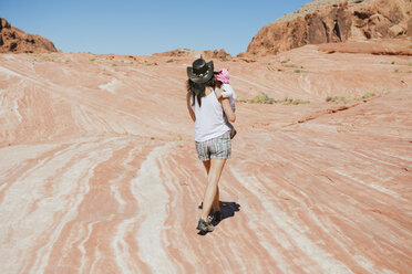 USA, Nevada, Valley of Fire State Park, back view of mother with baby girl on her arms in reddish landscape - GEMF02860