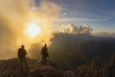Italy, Veneto, Dolomites, Alta Via Bepi Zac, mountaineers standing in mountainscape at sunset - LOMF00822