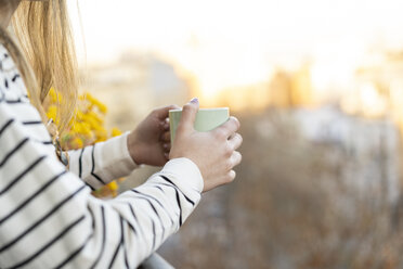 Junge Frau auf dem Balkon mit einer Tasse Kaffee, Teilansicht - AFVF02389