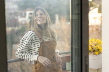 Porträt einer lächelnden jungen Frau, die sich auf einem Balkon entspannt - AFVF02393