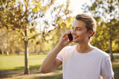 Junger Mann mit Smartphone in einem Park - JHAF00034