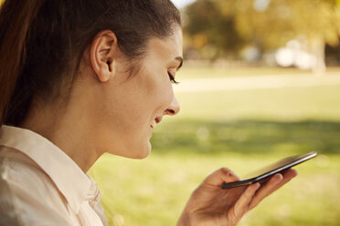 Happy young woman using smartphone in a park - JHAF00037