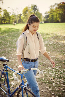 Junge Frau mit Fahrrad im Park - JHAF00038
