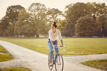 Young woman riding bike at a park - JHAF00048