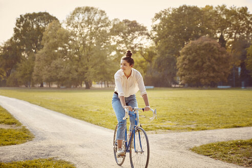 Junge Frau fährt Fahrrad in einem Park - JHAF00048