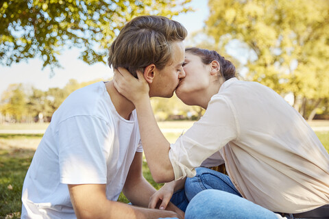 Junges verliebtes Paar küsst sich in einem Park, lizenzfreies Stockfoto