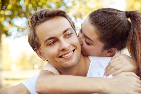 Glückliches junges Liebespaar küsst sich in einem Park - JHAF00065