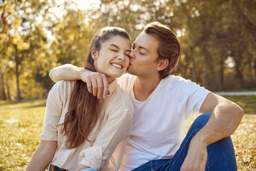 Happy young couple kissing at a park - JHAF00070