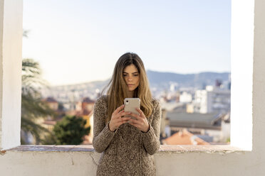 Ernste junge Frau schaut auf ihr Handy - AFVF02432