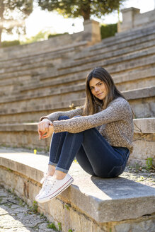 Porträt einer jungen Frau, die auf einer Treppe im Freien sitzt - AFVF02438
