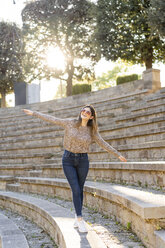 Glückliche junge Frau balanciert auf einer Treppe im Freien - AFVF02440