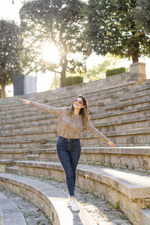 Glückliche junge Frau balanciert auf einer Treppe im Freien - AFVF02440