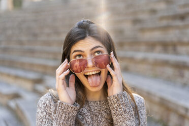 Playful young woman wearing sunglasses and grimacing - AFVF02442