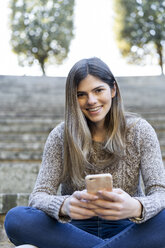 Porträt einer glücklichen jungen Frau mit Handy in der Hand - AFVF02451