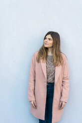 Young woman standing at a wall looking around - AFVF02462