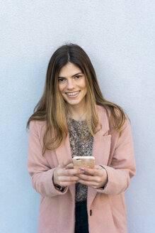 Porträt einer glücklichen jungen Frau mit Handy in der Hand - AFVF02463