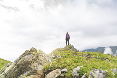 Mann steht auf einem Hügel und betrachtet die Landschaft in den Karpaten, Rumänien - SBOF01812