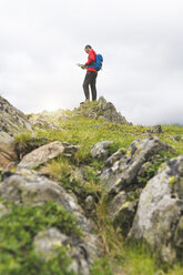 Mann steht auf einem Hügel und überprüft seine Landkarte in den Karpaten, Rumänien - SBOF01813