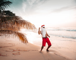 Thailand, man dressed up as Santa Claus posing on the beach at sunset - HMEF00211