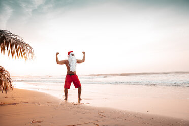 Thailand, man dressed up as Santa Claus posing on the beach at sunset - HMEF00212