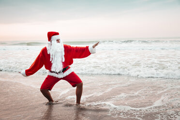 Thailand, man dressed up as Santa Claus posing on the beach at sunset - HMEF00215