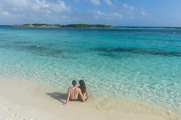 Karibik, Bahamas, Exuma, Pärchen am weißen Sandstrand mit Blick auf das türkisfarbene Wasser - RUNF01329