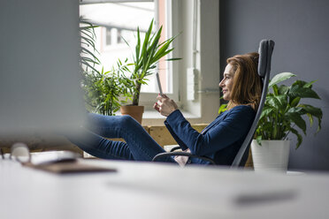 Reife Geschäftsfrau, die in einem nachhaltigen Büro arbeitet und ein digitales Tablet benutzt - MOEF02010