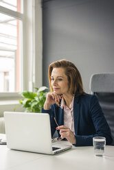 Businesswoman sitting in office, working on laptop - MOEF02050