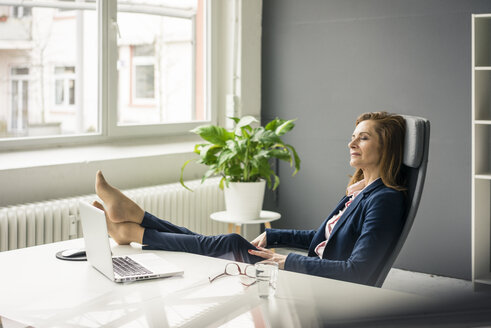 Geschäftsfrau entspannt sich im Büro und legt die Füße hoch - MOEF02051