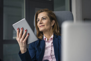 Selbstbewusste Geschäftsfrau, die im Büro sitzt und ein digitales Tablet benutzt - MOEF02053