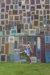 Indonesia, Bali, man walking at wall of wooden windows - KNTF02668