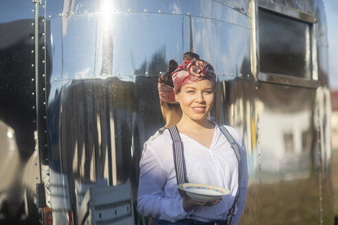 Porträt einer lächelnden jungen Frau an einem Imbisswagen, die einen Teller hält - SGF02235